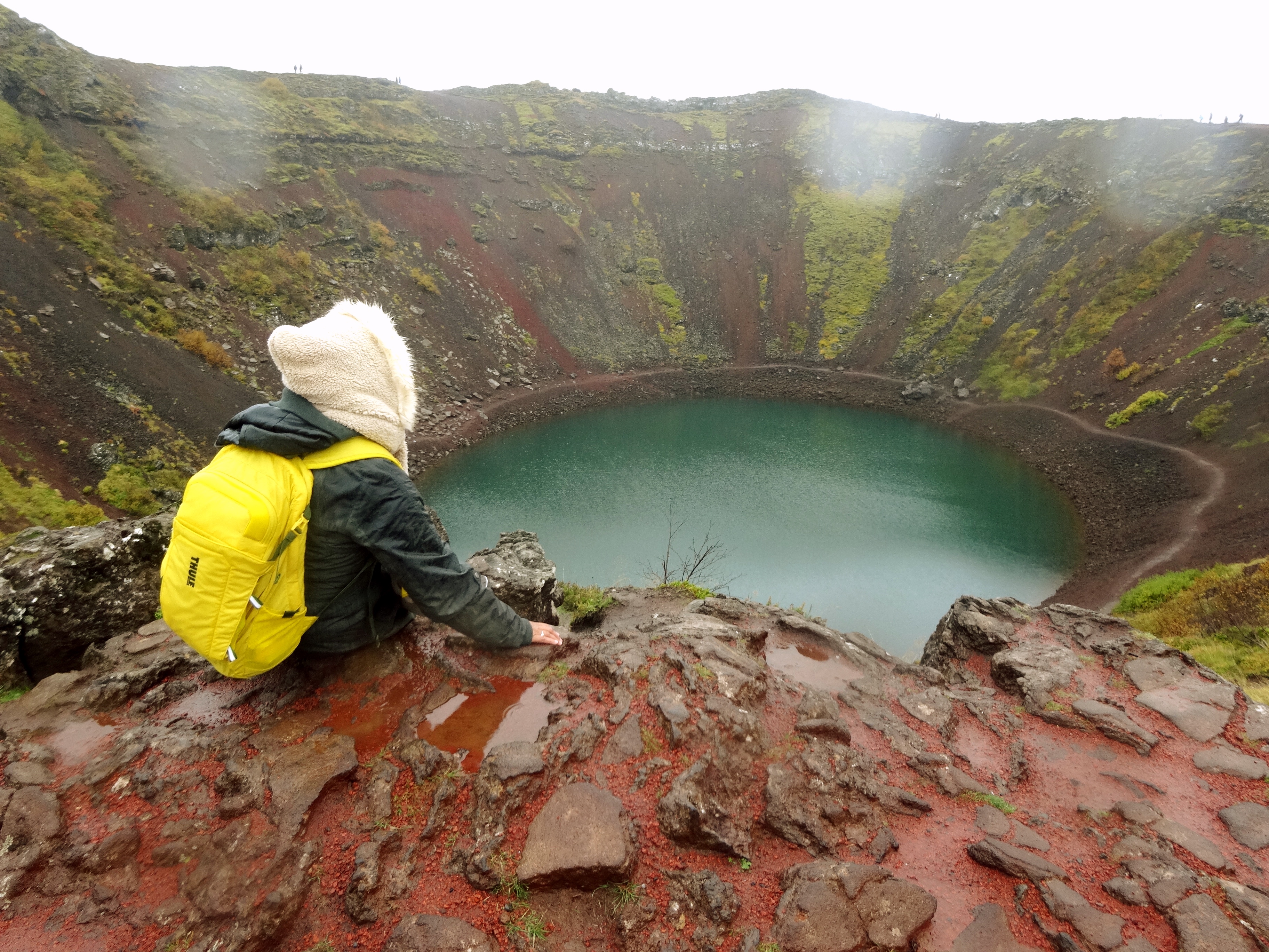 duduk di tepi Danau Kerið di Iceland dengan pemandangan kawah vulkanik dan air biru kehijauan
