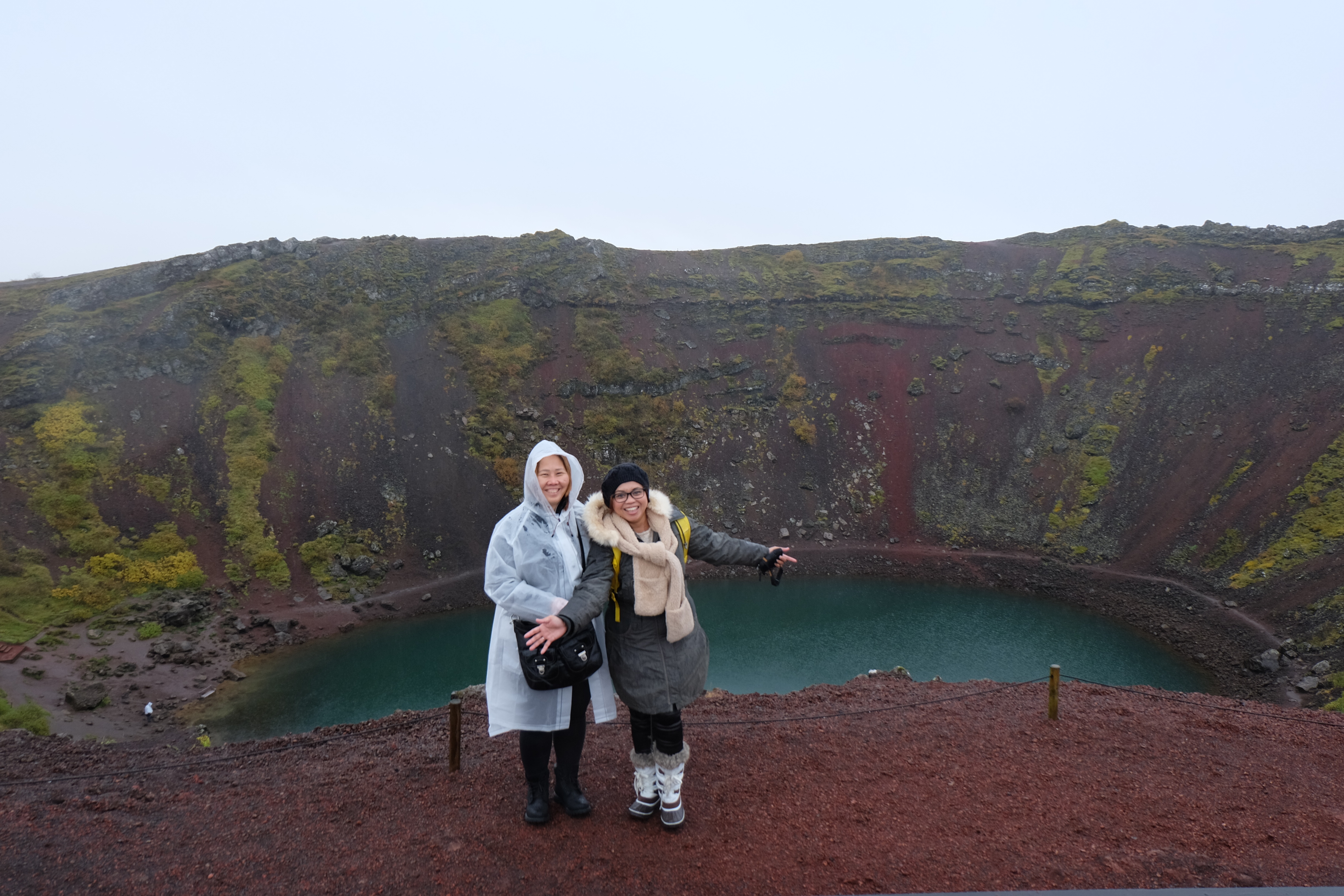 Kami berdiri di tepi Danau Kerið Iceland saat hujan dan angin dengan latar kawah vulkanik